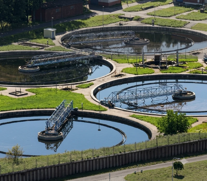 Aerial view of a large water treatment plant in the middle of a city, surrounded by water tanks, metal rods